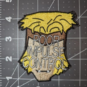 Peut inclure: Un patch brod&eacute; repr&eacute;sentant un personnage de dessin anim&eacute; avec des cheveux jaunes et un visage brun. Le texte "POOR IMPULSE CONTROL" est &eacute;crit en blanc sur le patch.