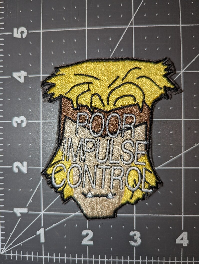 Peut inclure: Un patch brod&eacute; repr&eacute;sentant un personnage de dessin anim&eacute; avec des cheveux jaunes et un visage brun. Le texte "POOR IMPULSE CONTROL" est &eacute;crit en blanc sur le patch.