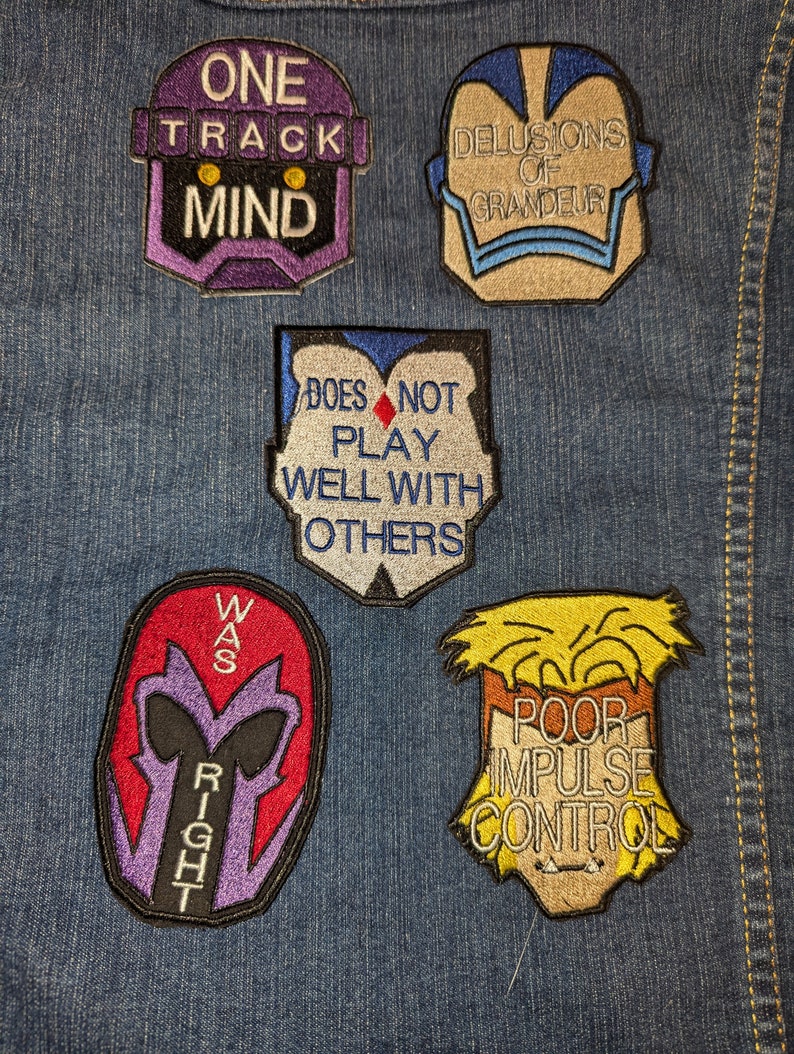 Peut inclure: Cinq patchs brod&eacute;s thermocollants avec des dictons diff&eacute;rents. Les patchs sont sur un fond en jean bleu. Les patchs sont violets, bleus, rouges, blancs et jaunes. Les dictons sur les patchs sont "One Track Mind", "Delusions of Grandeur", "Does Not Play Well With Others", "Was Right", and "Poor Impulse Control".