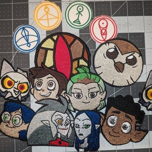May include: Embroidered patches featuring characters from the animated series The Owl House. The patches include King, Eda, Luz, Amity, Gus, Hunter, Willow, and the Owl House symbol.