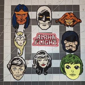 May include: A set of nine embroidered patches featuring characters from the Alpha Flight comic book series. The patches are colourful and feature various characters, including a Native American man, a woman with white hair, a man with a green face, and a woman with green hair. The patches are all in good condition and would be a great addition to any comic book fan's collection.