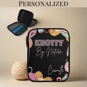 May include: A black rectangular zippered case featuring the text KNOTTY By Nature and the name Camille in white and pink script. The case is decorated with illustrations of yarn balls and knitting needles, with an open case showing needles inside.