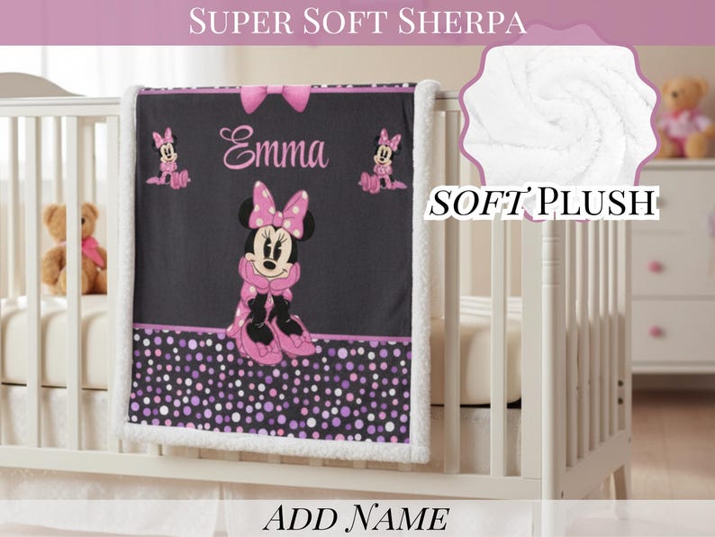 May include: A black and white sherpa baby blanket featuring a central graphic of Minnie Mouse in a pink polka dot dress and bow. The blanket includes the name Emma in pink script, a pink bow at the top, and a purple and pink polka dot border.