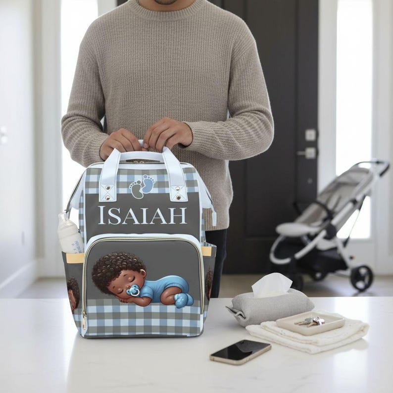 A man is holding a backpack with a baby image on it, standing in a room with a baby stroller and other items on the table.