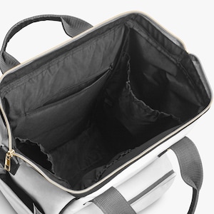 Peut inclure: Vue ouverte d'un sac fourre-tout gris et blanc avec un int&eacute;rieur noir. Le sac est dot&eacute; d'une poign&eacute;e sup&eacute;rieure et de bretelles. Une fermeture &eacute;clair dor&eacute;e longe le haut. L'int&eacute;rieur comporte plusieurs poches.