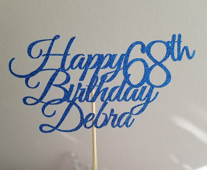 Pode incluir: Topper para bolo de glitter azul com o texto "Happy 68th Birthday Debra".
