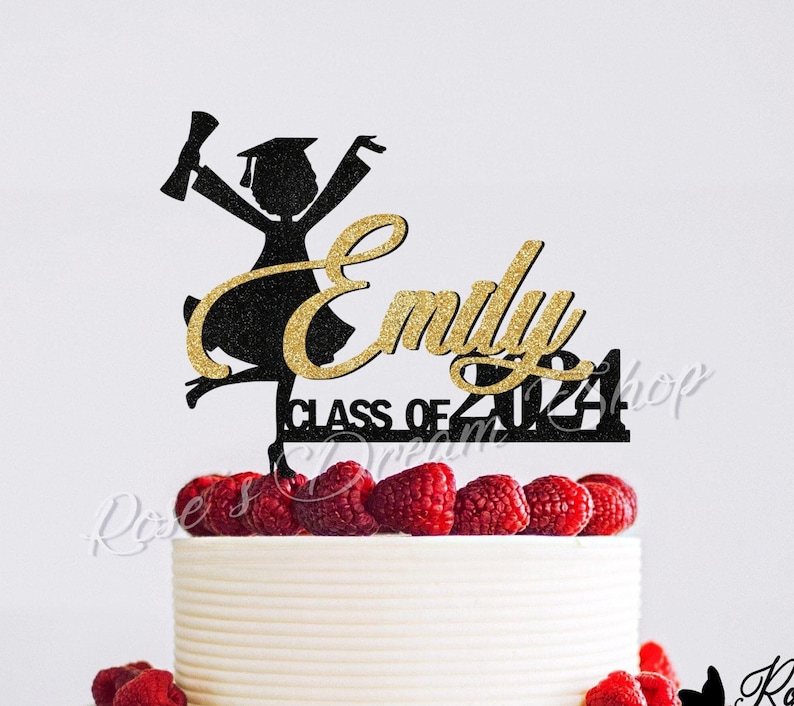 May include: Black and gold glitter graduation cake topper with a silhouette of a female graduate, the name "Emily" and the text "Class of 2024".