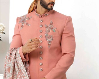 May include: A pink long-sleeved kurta with floral embroidery and button fastenings. The kurta is paired with a matching pink dupatta with a floral pattern. The man is wearing a gold turban with a white feather.