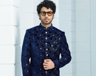 Puede incluir: Una kurta de terciopelo azul marino de manga larga con un patrón floral y un cierre de botón plateado. La kurta se lleva con pantalones blancos y zapatos negros.
