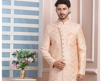 Puede incluir: Una kurta de hombre de color melocotón con un patrón blanco y un cierre de botón blanco. La kurta se combina con pantalones blancos y zapatos blancos. La imagen también incluye una mesa blanca con un arreglo floral.