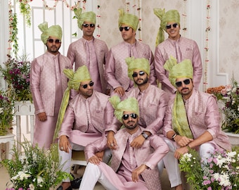 May include: A group of men wearing pink and green traditional Indian clothing. They are all wearing sunglasses and green turbans. The men are standing in a room with white walls and floral decorations.