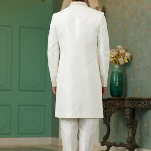 Puede incluir: Una kurta blanca de manga larga con un sutil estampado floral. La kurta tiene un cuello mandar&iacute;n y se lleva con pantalones blancos.