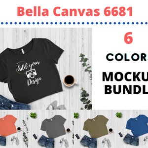 May include: Mockup bundle of six different colored cropped t-shirts. The t-shirts are laid out on a white wood background with denim shorts, a phone, and a cup of coffee. The t-shirts are all the same style, but in different colors: coral, gray, olive green, and blue. The text "Add your design" is on the black t-shirt.