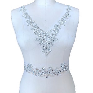 May include: A crystal rhinestone applique with a V-neck design and a separate waist band design. The applique is made of clear rhinestones and is perfect for adding sparkle to a dress or other garment.