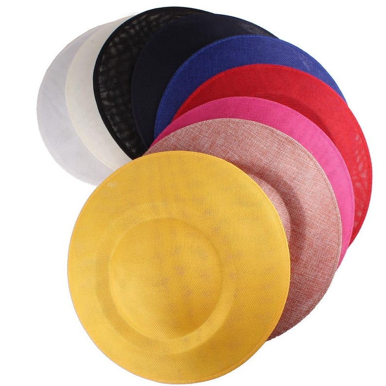 K&ouml;nnte beinhalten: Ein Satz von neun runden Hutbasen in verschiedenen Farben, darunter Wei&szlig;, Schwarz, Marineblau, K&ouml;nigsblau, Rot, Rosa und Gelb. Die Basen sind aus gewebtem Material und f&uuml;r die Hutmacherei bestimmt.