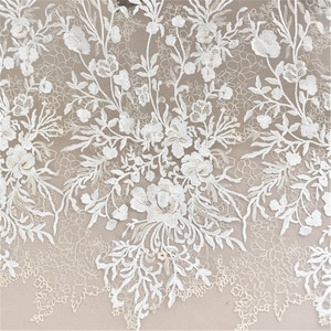 May include: White floral lace fabric with a delicate pattern of flowers and leaves. The lace is sheer and has a soft, romantic feel.