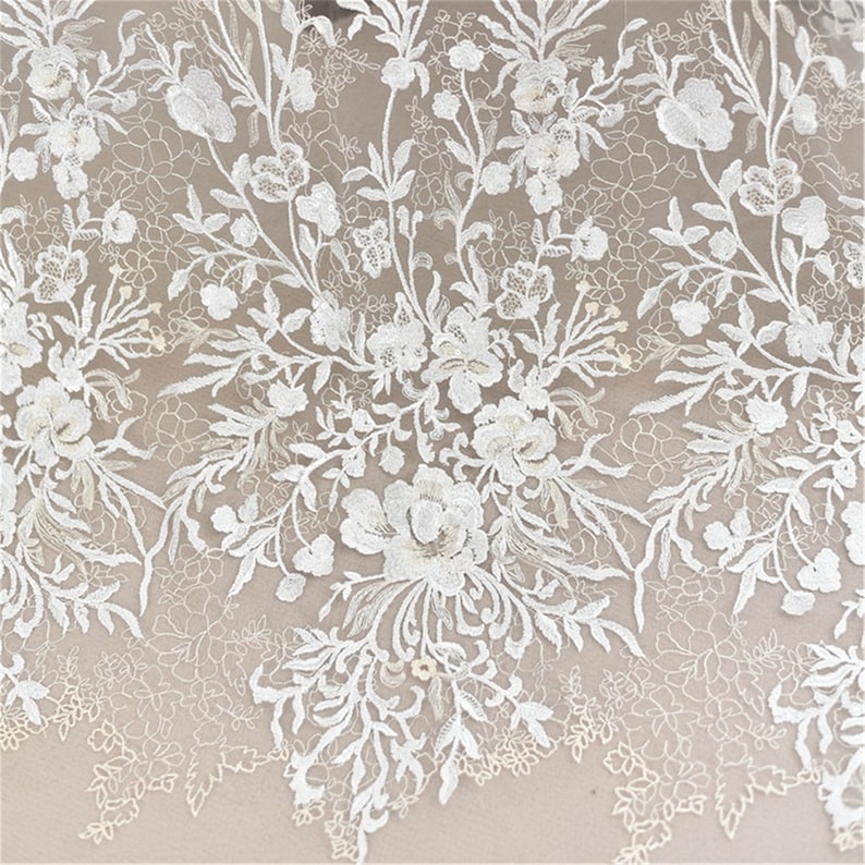May include: White floral lace fabric with a delicate pattern of flowers and leaves. The lace is sheer and has a soft, romantic feel.