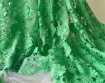 Puede incluir: Tela de encaje floral verde con un diseño delicado e intrincado. El encaje presenta un patrón repetitivo de flores y hojas, creando un aspecto hermoso y elegante.