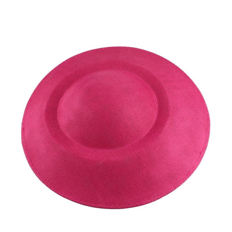 K&ouml;nnte beinhalten: Ein runder, flacher Hut aus geflochtenem Stroh in leuchtendem Pink.
