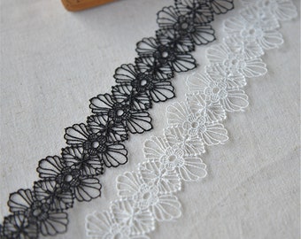 Puede incluir: Borde de encaje negro y blanco con un diseño floral. El encaje es delicado e intrincado, con pequeñas flores y hojas.
