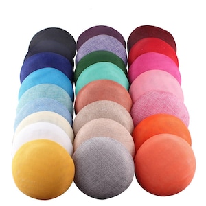 Peut inclure: Une collection de bases de chapeaux rondes en tissu de différentes couleurs, dont le marine, le turquoise, le rose et l'orange. Les chapeaux sont disposés en rangées soignées, présentant une variété de couleurs et de textures. Fournitures de chapellerie.