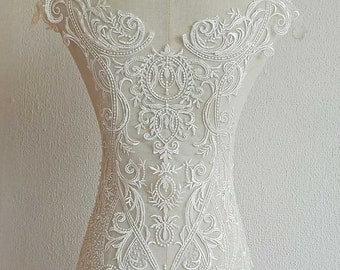 May include: White beaded lace applique with a floral design. The lace is delicate and intricate, with a scalloped edge. This applique is perfect for adding a touch of elegance to any garment.