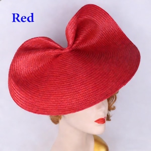 Peut inclure: Un chapeau de soleil rouge vif avec un large bord et un design sculpté unique. Le chapeau est fait de matériau tissé et porte le mot "Red" en bleu. Le chapeau est présenté sur une tête de mannequin.