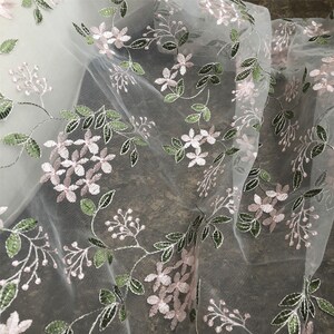 May include: White sheer fabric with delicate pink and green embroidered floral designs.