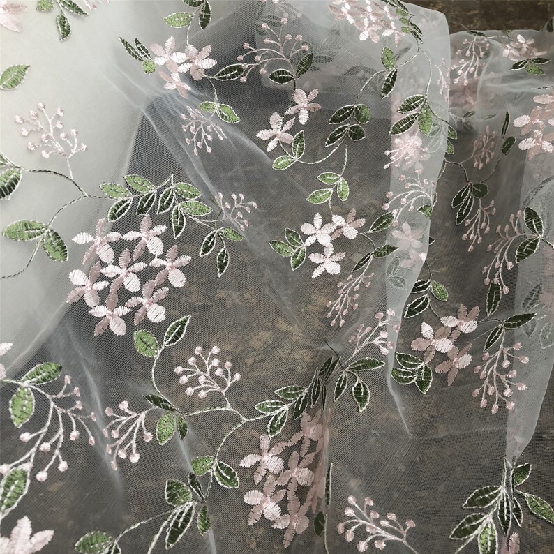 May include: White sheer fabric with delicate pink and green embroidered floral designs.
