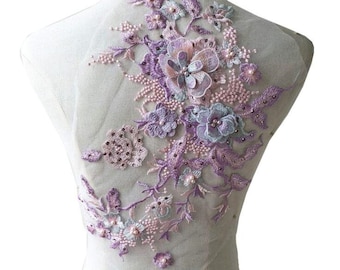 May include: A delicate floral applique with pink and purple flowers, pearls, and rhinestones. The applique is perfect for adding a touch of elegance to clothing, accessories, or home decor.