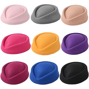 May include: A collection of nine pillbox hats in various colours: pink, grey, beige, fuchsia, yellow, purple, burgundy, blue, and black. Each hat features a rounded crown and a flat, brimless design.