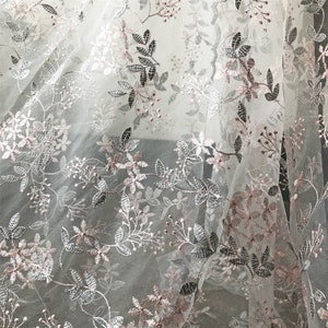 May include: White tulle fabric with a delicate floral embroidery pattern in silver and pink.