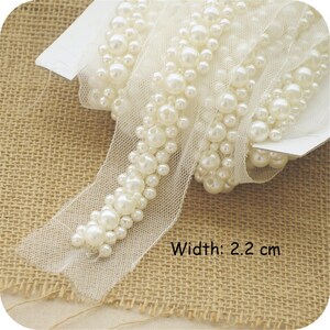 Op de afbeelding: Witte pareltrim met een delicate mesh-rug. De trim is 2,2 cm breed.