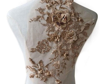 May include: Gold floral applique with pearl accents. This delicate lace embellishment features intricate floral designs and sparkling beads, perfect for adding a touch of elegance to clothing, accessories, or home decor.