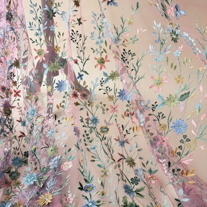 May include: Sheer pink fabric with embroidered floral patterns. The embroidery features a variety of colorful flowers in shades of blue, pink, yellow, and green, with delicate green leaves and stems. The fabric is semi-transparent.