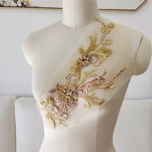 May include: Gold and pink floral applique with sequins and rhinestones on a sheer mesh fabric. This applique is perfect for adding a touch of elegance to any garment.