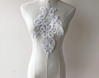 May include: White lace applique with a delicate floral design. This intricate embellishment is perfect for adding a touch of elegance to clothing, accessories, or home decor projects.