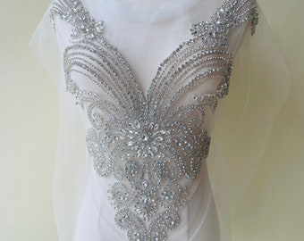 May include: A silver rhinestone applique with a V-neck design. The applique is made of small, sparkling rhinestones and is perfect for adding a touch of glamour to any garment.