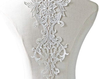 May include: White lace applique with a floral design. The applique is delicate and intricate, with a large central flower and smaller flowers and leaves surrounding it. It is perfect for adding a touch of elegance to any garment.