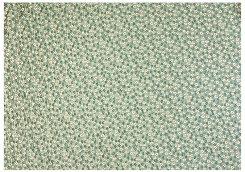 May include: A green fabric with a white floral pattern. The fabric is covered in small white flowers.