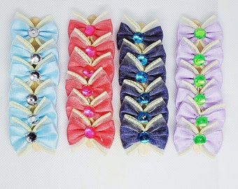 Puede incluir: Un conjunto de 10 lazos hechos a mano con tul y purpurina de diferentes colores. Los lazos están unidos a palos de madera y tienen una variedad de piedras de colores en el centro.