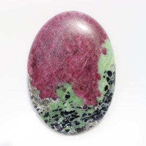 Może przedstawiać: Gładki, owalny, zielono-różowy kamień szlachetny z czarnymi plamkami.