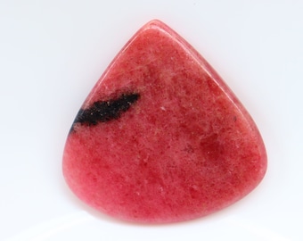 Puede incluir: Una piedra preciosa rosa y negra con forma triangular. La piedra preciosa tiene una superficie lisa y pulida.