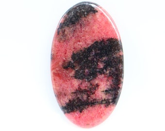 Puede incluir: Una piedra preciosa ovalada cabujón de color rosa y negro. La piedra tiene un patrón de remolino de rosa y negro.