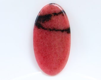 Puede incluir: Una piedra preciosa ovalada cabujón de color rosa y negro con una superficie lisa y pulida. La piedra preciosa tiene un patrón de líneas negras en espiral sobre un fondo rosa.