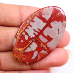 May include: Oval shaped red, white, and yellow jasper cabochon with a swirling pattern.
