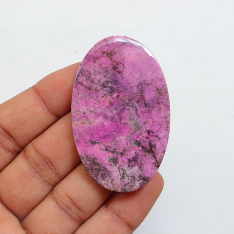 May include: A pink and gray oval cabochon gemstone with a marbled pattern.