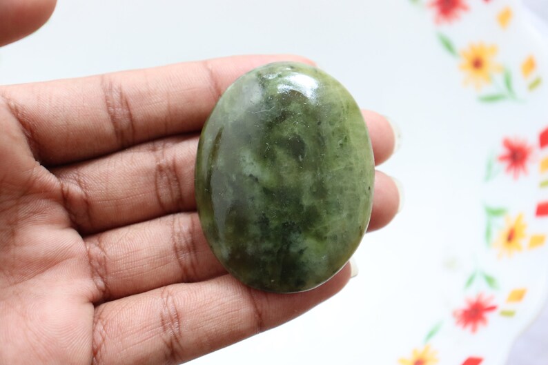 May include: A smooth, oval-shaped green stone with a marbled pattern. The stone is polished and has a glossy finish.