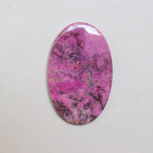 May include: A pink and grey oval cabochon gemstone with a marbled pattern.