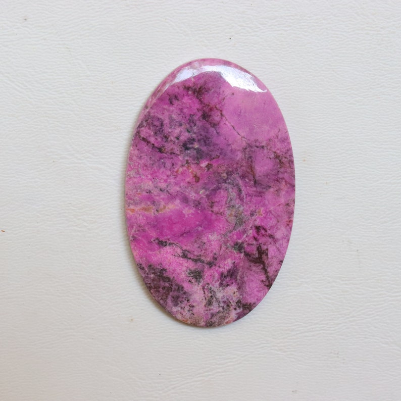 May include: A pink and grey oval cabochon gemstone with a marbled pattern.
